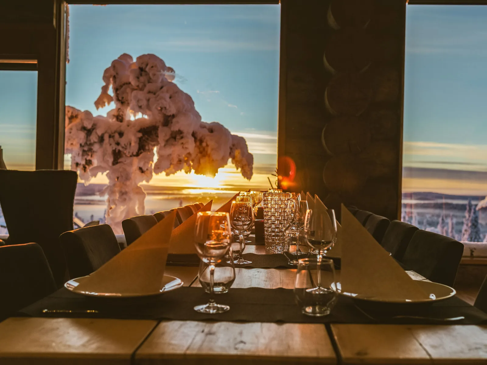 A candlelit dining table at Uuvana overlooking the frozen fell at sunset