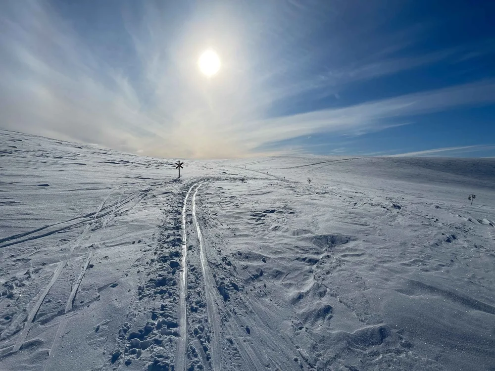 A ski track crossing an open fell beneath a winter halo